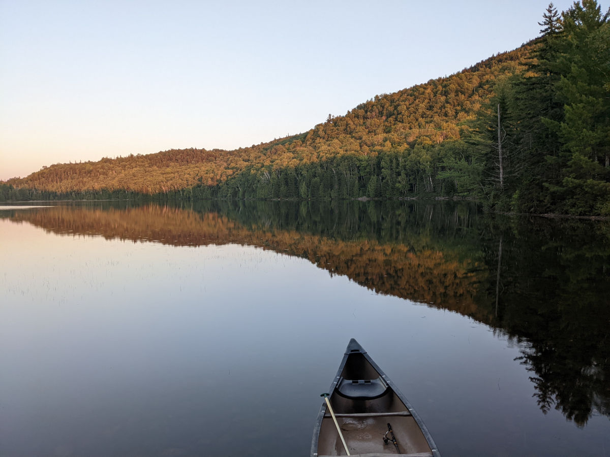 Reflection on calm lake with canoe in foreground