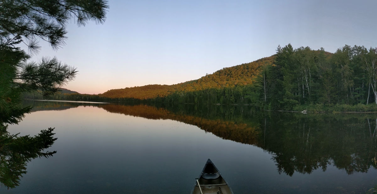 Reflection on calm lake with canoe in foreground wider angle