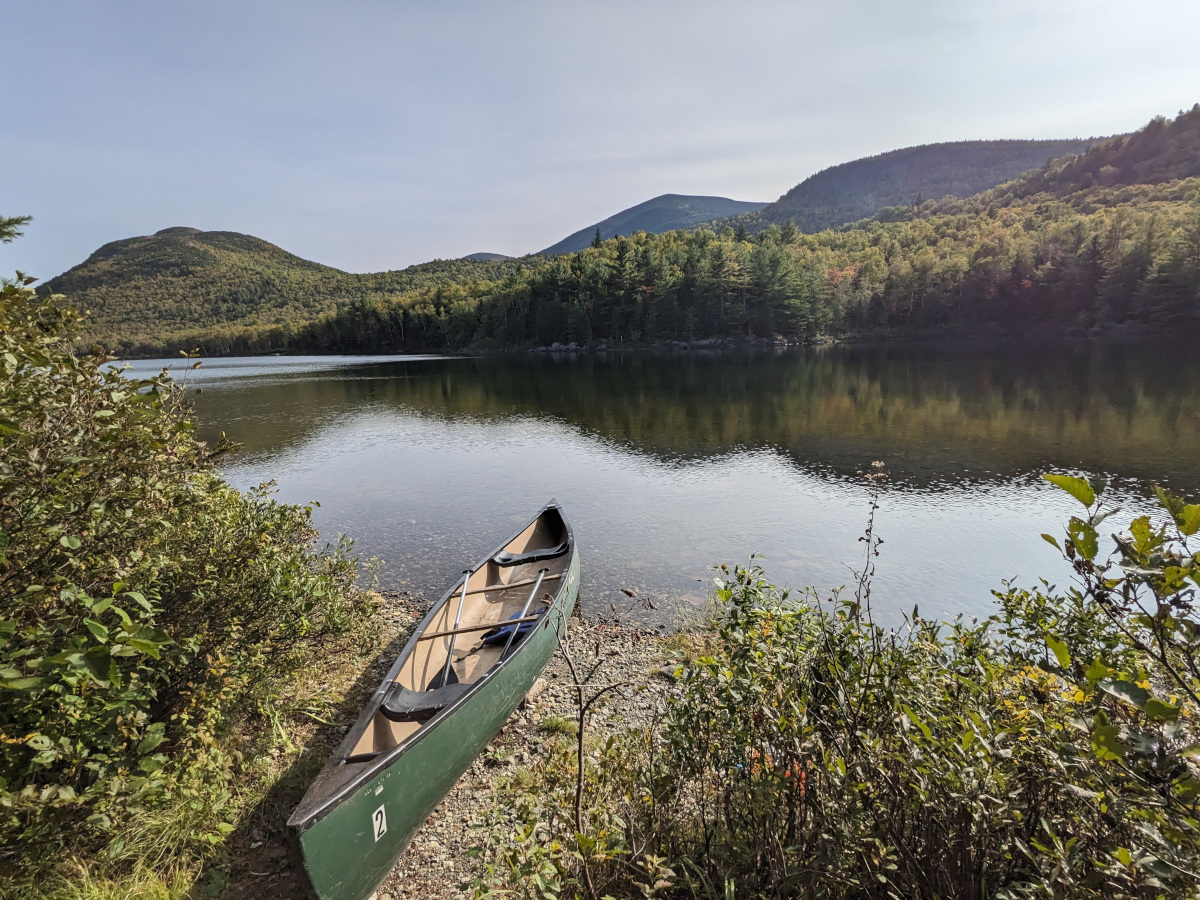 Canoe on the shore of Middle Fowler Pond with mountains in the background
