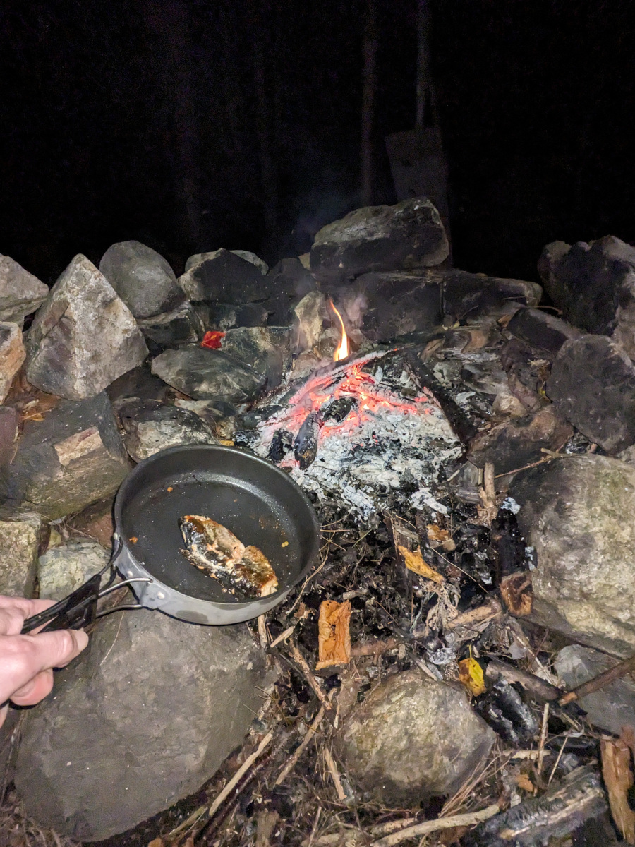 Fish fried in a pan being removed from a fire