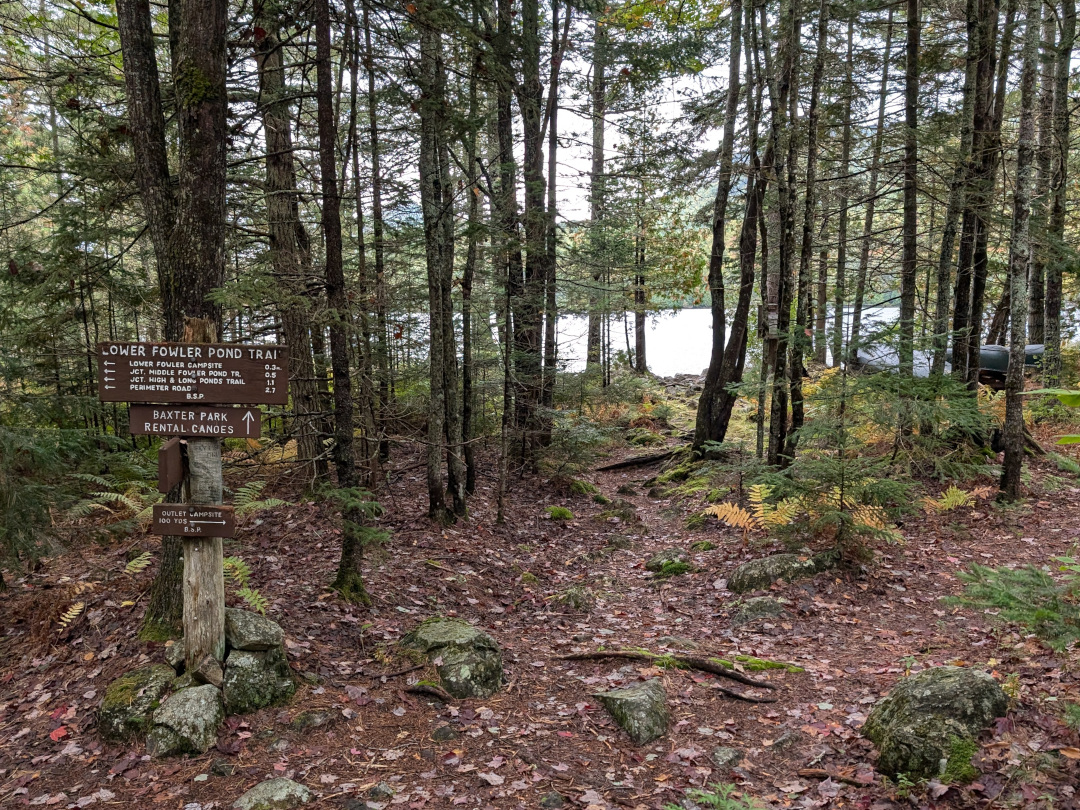 Lower Fowler Pond canoe rental sign with canoes and lake in background