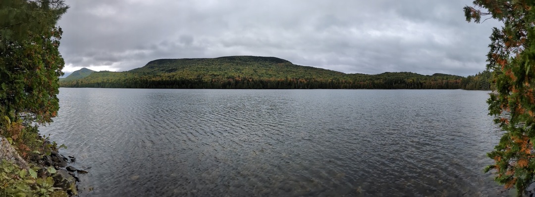 Panorama of slightly ripply lake with two mountains in the background