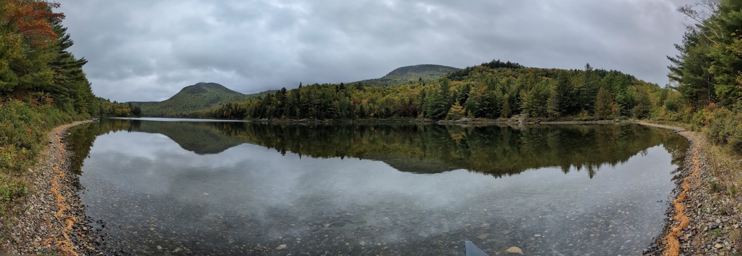 Panorama of smooth lake with two mountains in the background