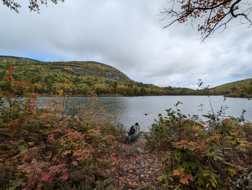 Panorama of lake with canoe in foreground and mountain in background