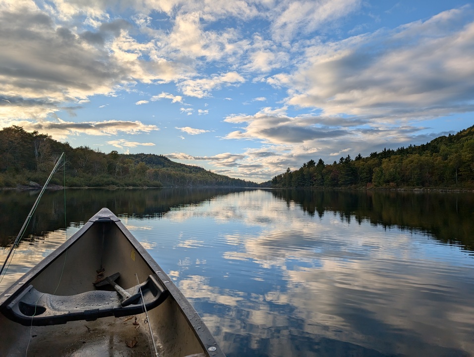 Calm misty lake, blue sky, canoe and fishing rods