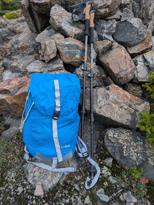 Packable backpack full of stuff next to trekking poles