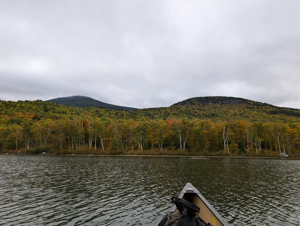 Canoe with two mountains in background, one partially obscured by cloud