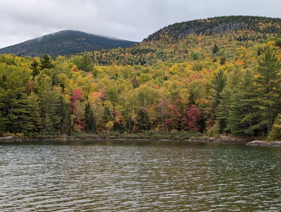 Slightly ripply lake with two mountains in background