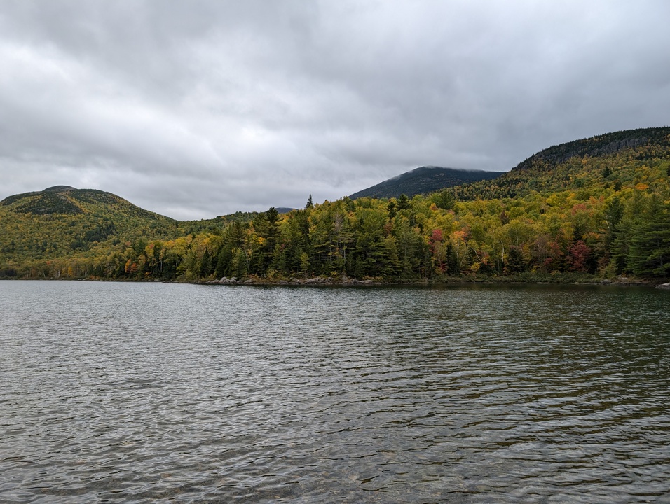 Slightly ripply lake with three mountains in background