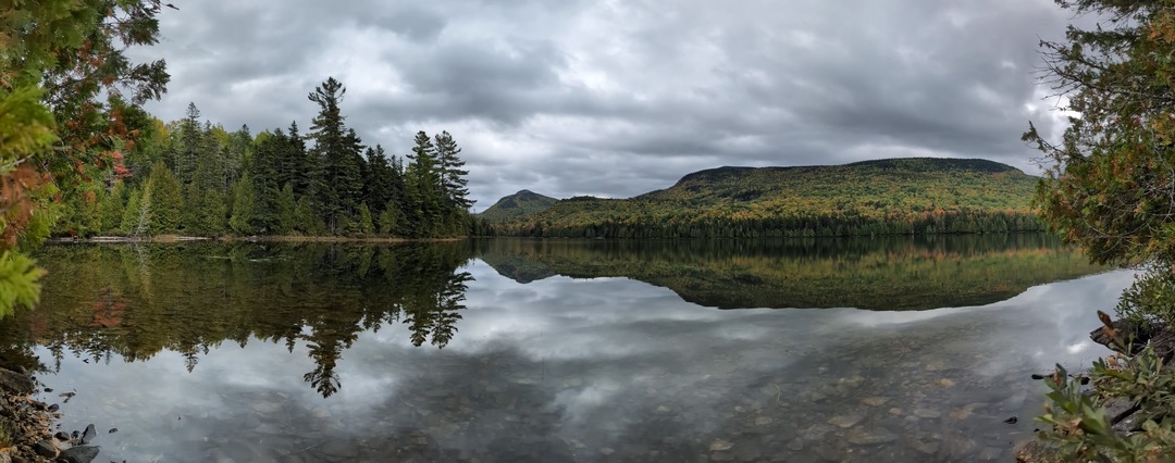 Panorama of calm lake with mountain in background and reflected on lake