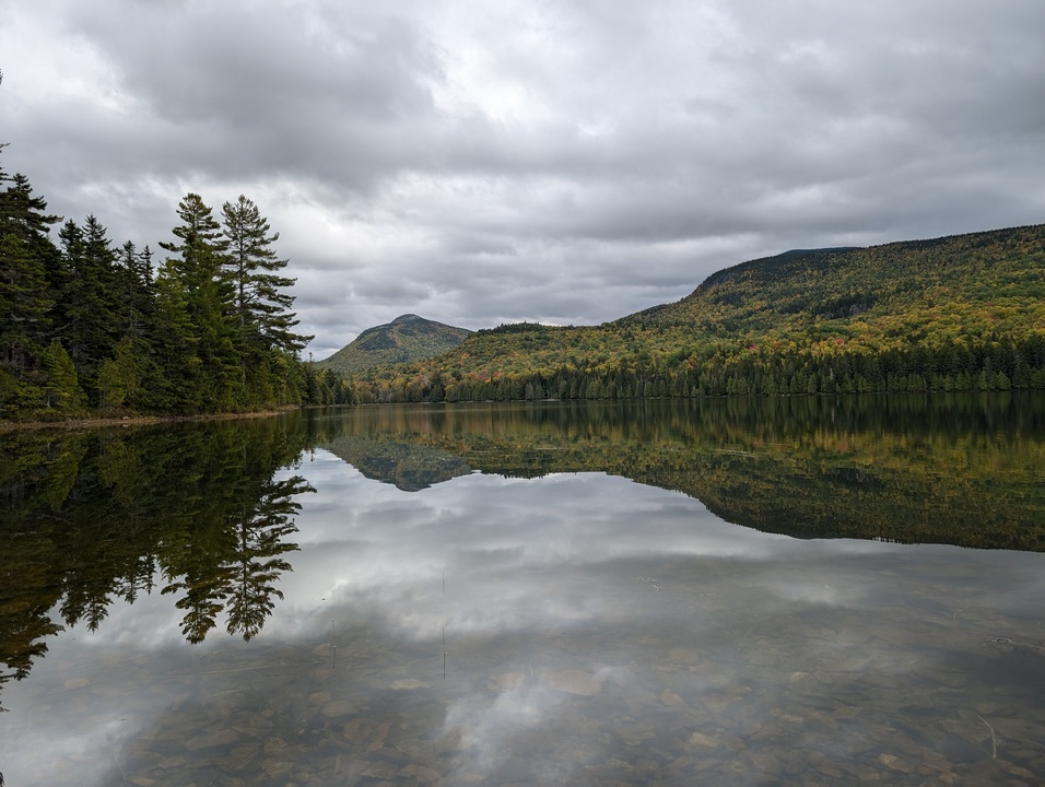 Panorama of calm lake with mountains in background and reflected on lake