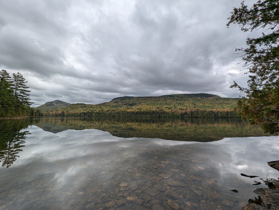 Panorama of calm lake with mountains in background and reflected on lake