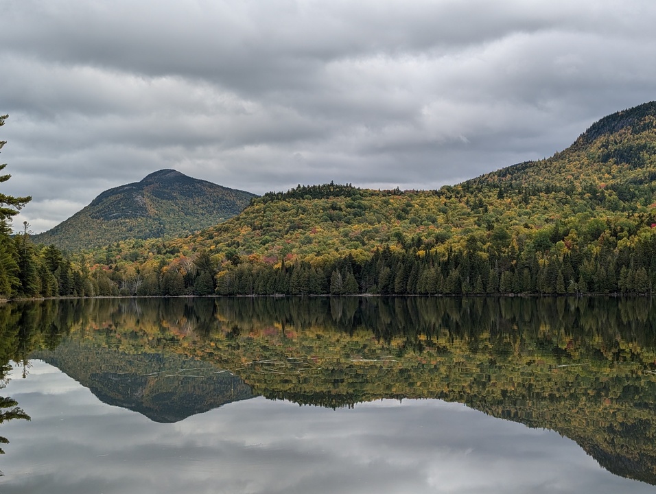 Two mountains reflected in lake with fall colored trees