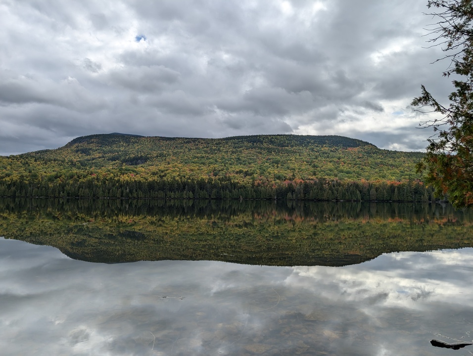 Long mountain reflected in lake with fall colored trees