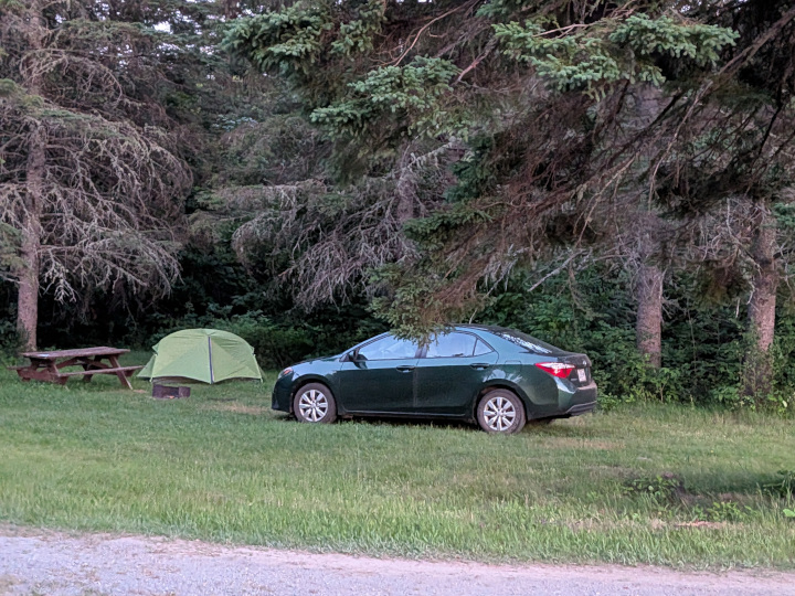 Car, tent, picnic table right next to dirt road