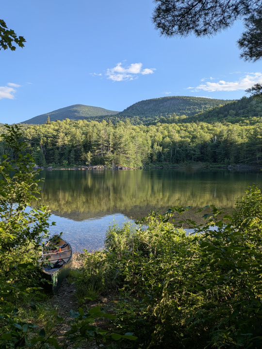 Canoe in front of calm lake and mountains