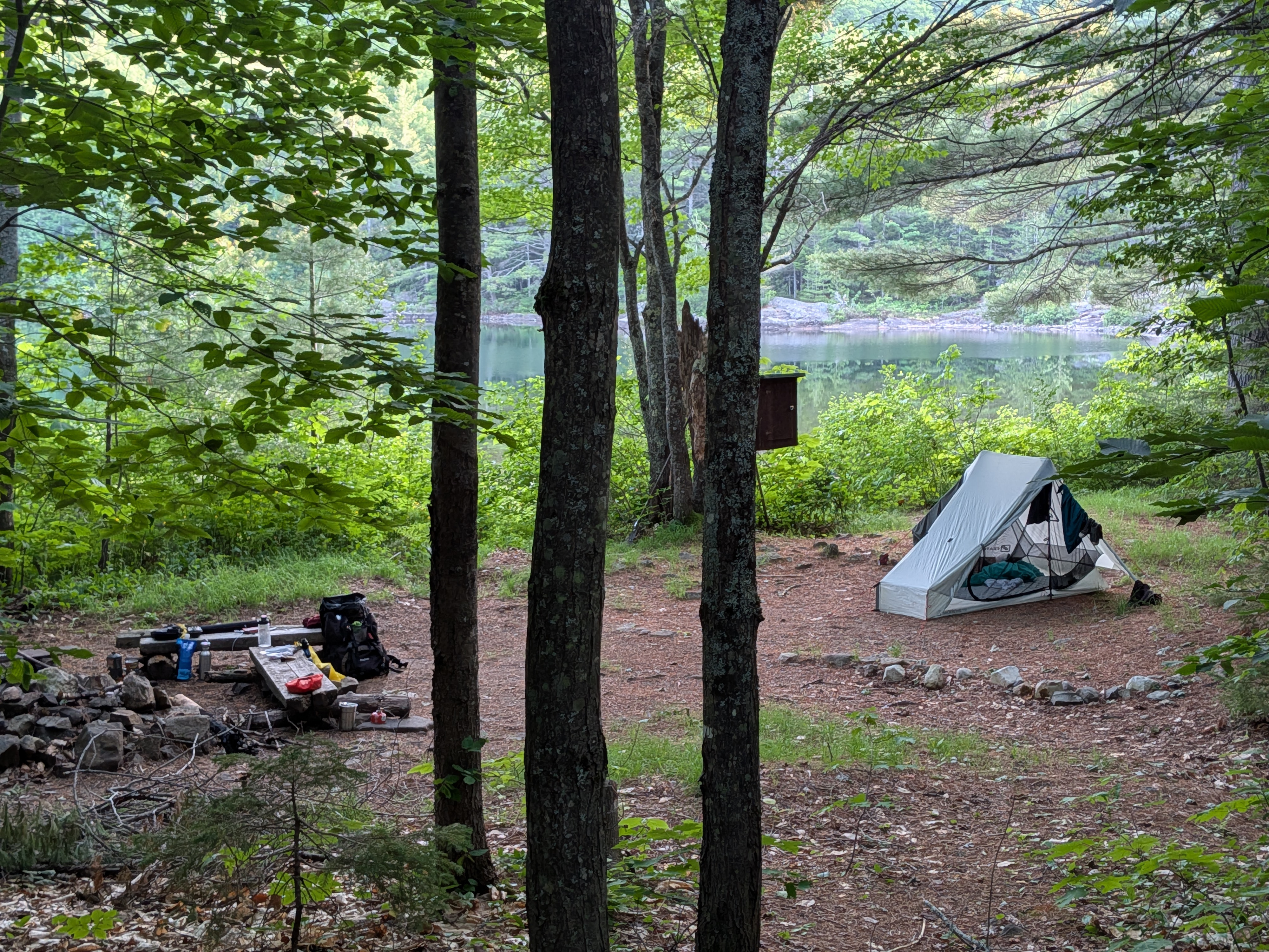 Tent and gear at camp site with lake in background